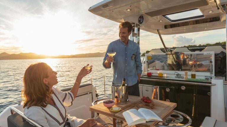 Couple toasting glasses on the deck of a powerboat with the sunset in the background